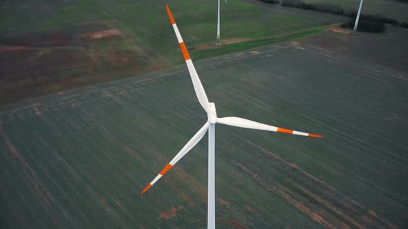 Top View Drone Tilts Down Directly Above Windmill Turbine with Red Blade Stripes, Alternative Energy