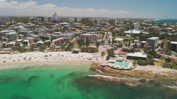 Aerial drone footage of ocean waves on a busy Kings beach, Caloundra, Australia