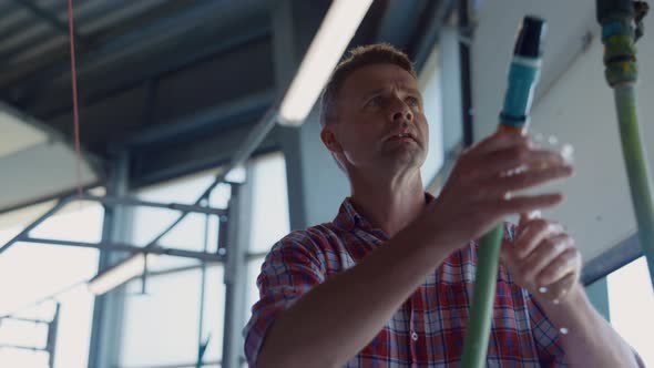 Farm Worker Washing Dairy Producing Automat on Robotic Barn Using Hose Close Up