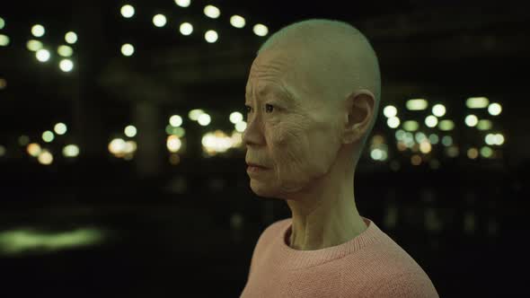 Old Asian Woman in City at Night