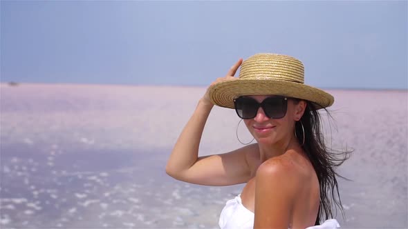 Woman in Hat Walk on a Pink Salt Lake on a Sunny Summer Day.