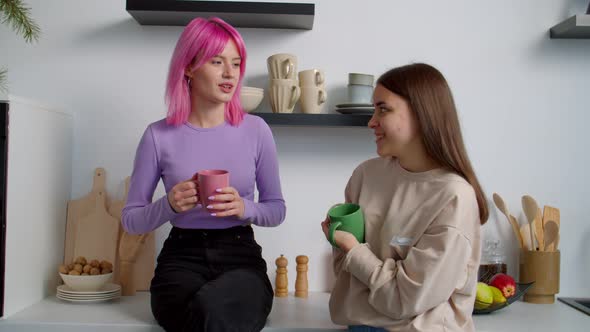 Cheerful Lovely Female Roommates Chatting Over Coffee in Kitchen at Dorm
