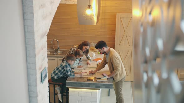 High Angle View of Parents Father and Mother Helping Children with Homework in Kitchen