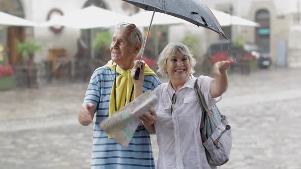 Happy Senior Tourists Stand Downtown and Enjoy the Rainy Weather in Lviv