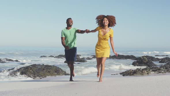 African American couple running side by side at beach