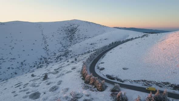 Yellow Van Driving on Winter Mountain Road, Taking Big Right Turn. Scenic Mountain Landscape