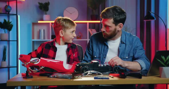 Dad Learning the Content of Toy Car and Does Not Allow to Touch Wires to His Interested Son