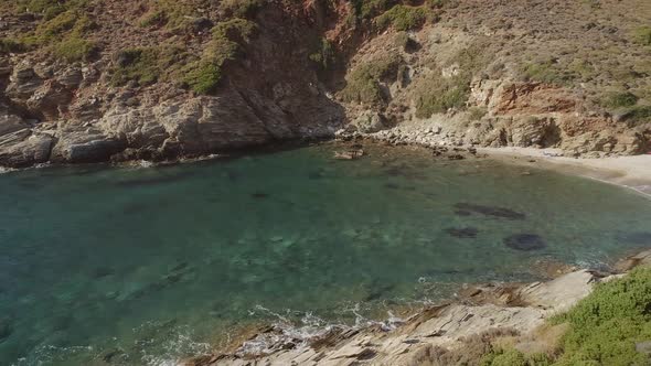 Aerial view of an empty small beach with turquoise water and stones in Greece.