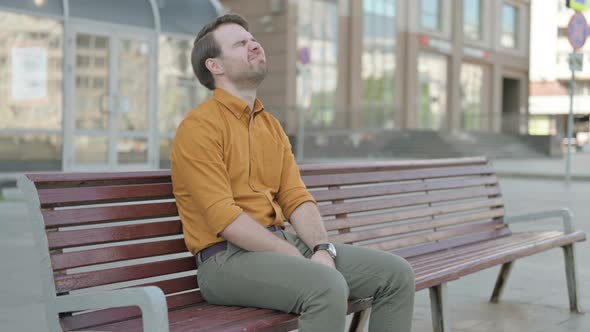 Tense Young Man Feeling Frustrated while Sitting Outdoor on Bench