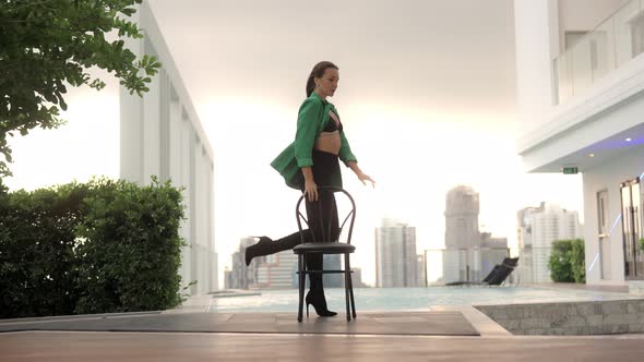 Dancer Posing With Chair By Infinity Pool In City