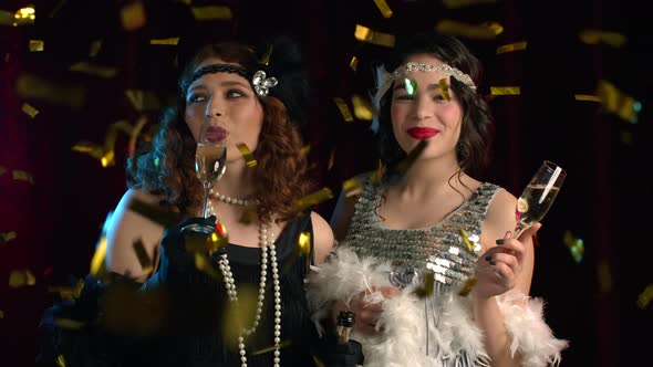 Beautiful Flappers Women Dressed in Roaring Twenties Time Drinking Champagne Under Confetti Rain