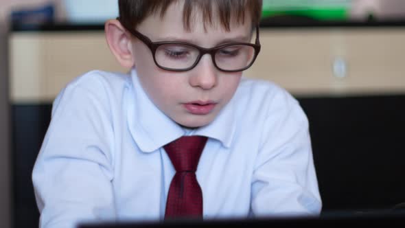 focused caucasian student in glasses for 7 years at home is engaged on a gadget doing homework