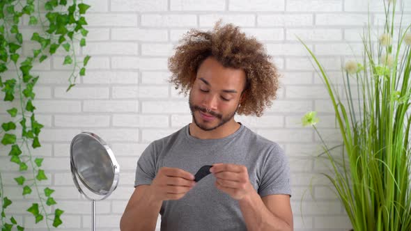 Young man massaging face with gua sha stone at home