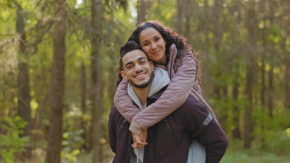 Young Hispanic Happy Couple in Love in Autumn Park Handsome Guy Holding Girl on Back Cute Girlfriend