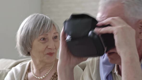 Curious Elderly Couple Inspecting VR Goggles