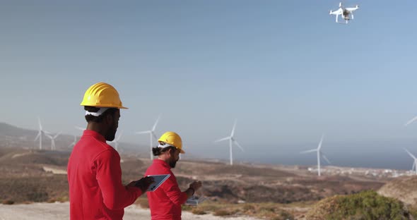 Multiracial engineer men working together on a windmill farm using digital tablet and drone