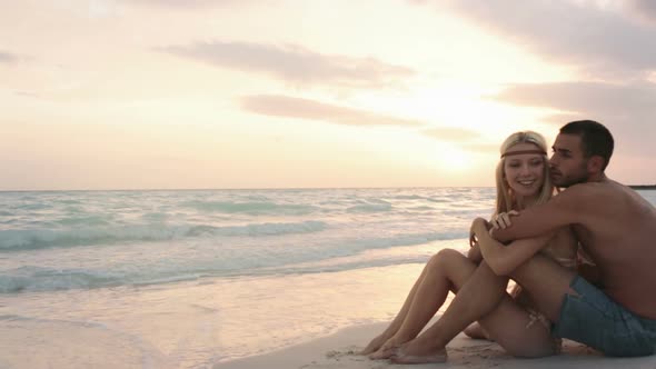 Young Man Woman Couple in Love Hugs and Enjoys Sunrise or Sunset on Ocean Beach Seaside in Summer