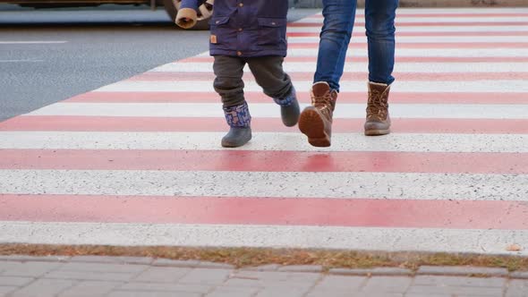 Mom and child cross the road at the zebra crossing.