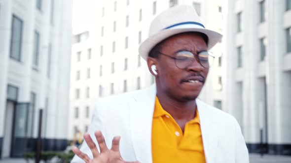 African American man in hat and wireless headphones listens to music