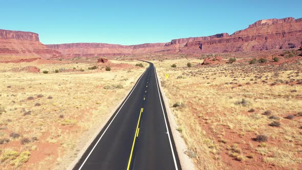 Fly Over Highway In Usa Desert Among Red Rocks Formation Aerial View