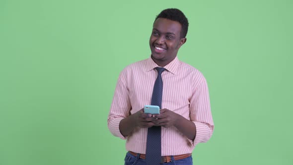 Happy Young African Businessman Thinking While Using Phone