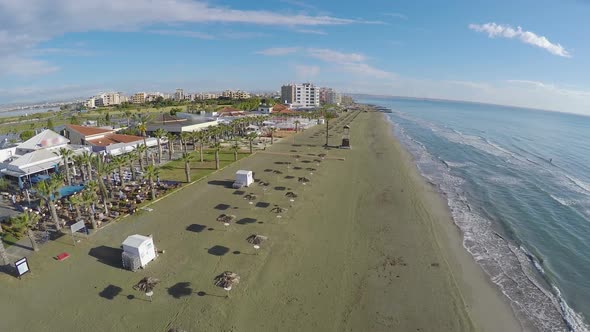 Aerial view above empty beach with straw parasols, coastline in Larnaca, Cyprus