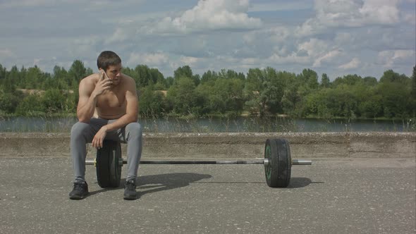 Athletic Bearded Man with Muscular Body Having Phone Call After Training Outdoor