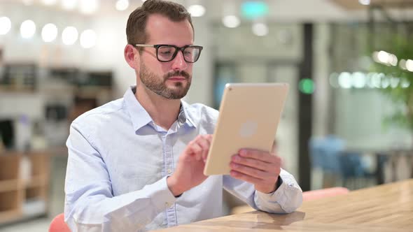 Serious Businessman Using Tablet in Office 