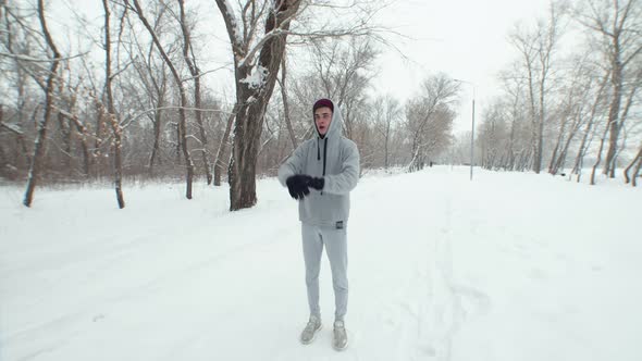 Caucasian Man on Winter Run Runs in Gray Tracksuit with Hood