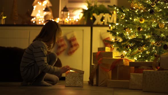 Daughter Opening Present Under Christmas Tree