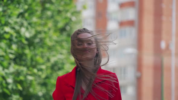 Pretty smiling curly woman in stylish look confidently walks down the street, touches hair