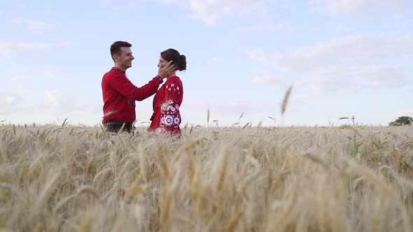 Couple in love hugging at sunset in wheat. Red clothing. Slow motion