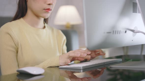 Young Asian Businesswoman Working From Home and Using Desktop Computer While Sitting in Living Room