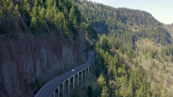 Tracking shot of cars traveling on highway in a location with steep and scenic terrain.