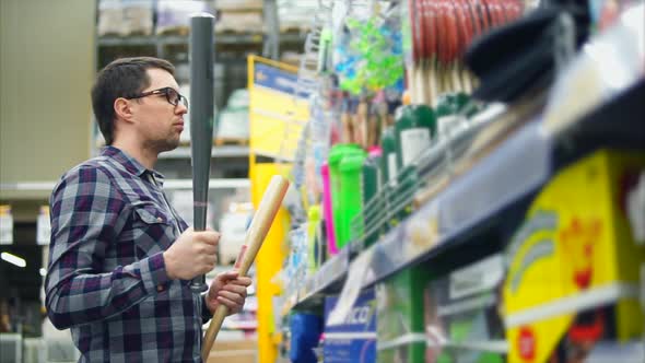 A Man in Glasses Selects a Baseball Bat for a Teenager in a Grocery Store