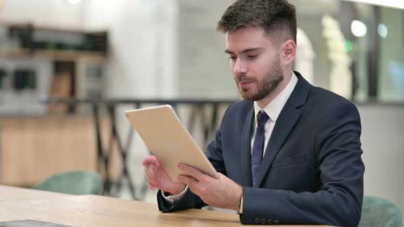 Excited Young Businessman Celebrating Success on Tablet in Office