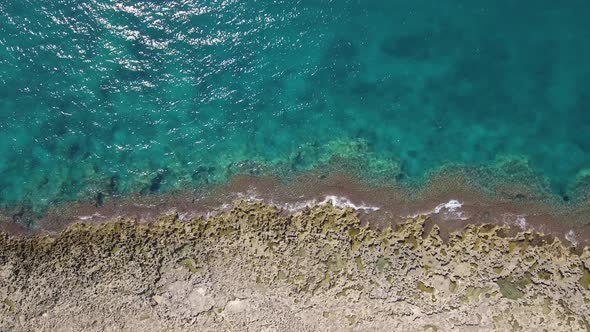 Aerial top view of coastline with waves on the rocks