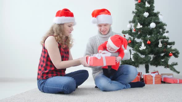 Family Holiday and Christmas Concept. Young Mother and Father with a Child Unpack a Christmas