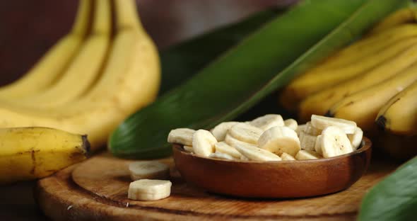 The Banana Slices on the Plate Rotate Slowly with a Bunch of Bananas and Leaves
