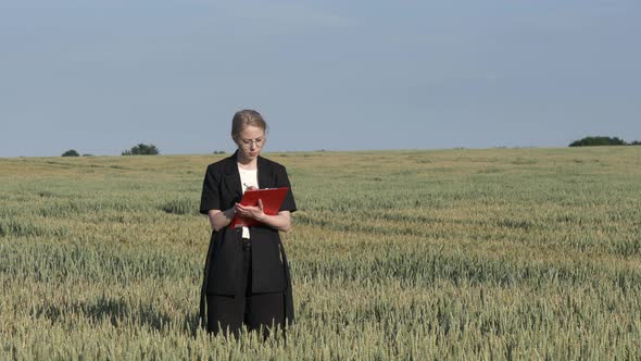 employee of an agricultural firm with notebook checks the quality of wheat in the field