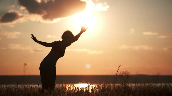 Silhouette of Young Beautiful Girl Practicing Yoga at Sunset