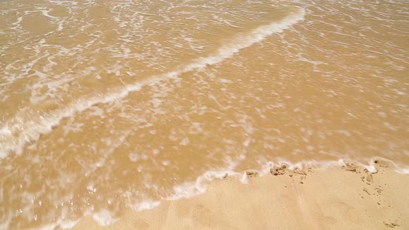 HOLIDAY written in the beach sand washed aways by waves.