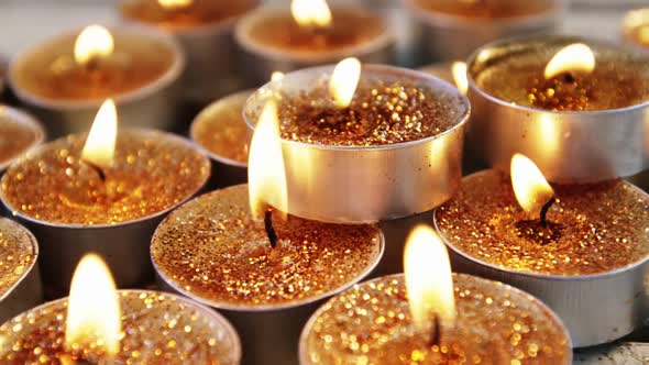 Close-up of burning candles on wooden plank