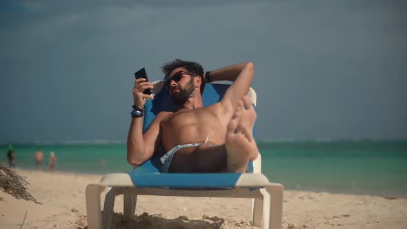 Traveler Resting Beach Hotel Luxury. Man Relaxing On Tropical Beach. Man Lies On Sunbed On Vacation.