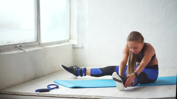 Young Woman Is Engaged in Leg-stitching After Active Physical Training