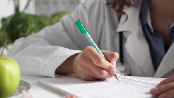 A Woman Doctor Writes Down The Patient's Medical History, The Doctor Writes In A Notebook