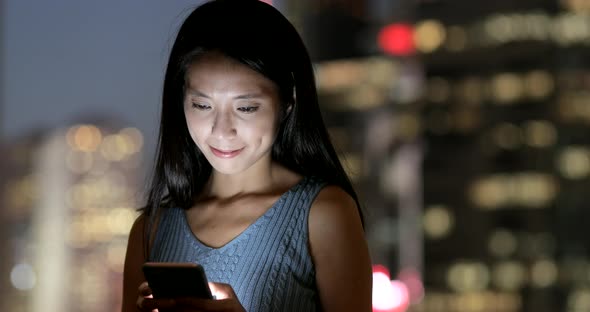 Woman using smart phone in Hong Kong city at night 