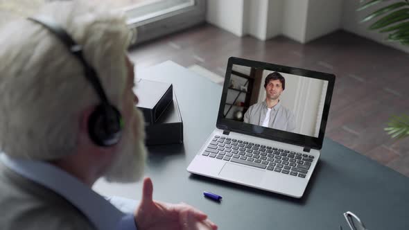 Over the Shoulder View of an Elderly Man Video Call To Son Using a Laptop. The Concept of Family