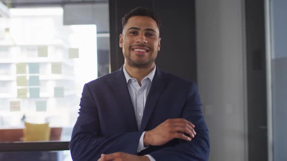 Portrait of mixed race businessman with arms crossed smiling looking at camera