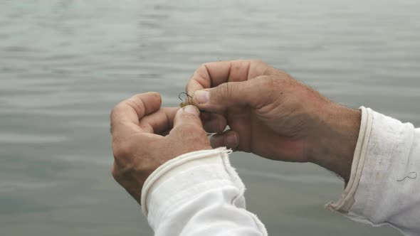 Close up of male hands with fishing gear. Fisherman preparing fishing bait for fishing. 